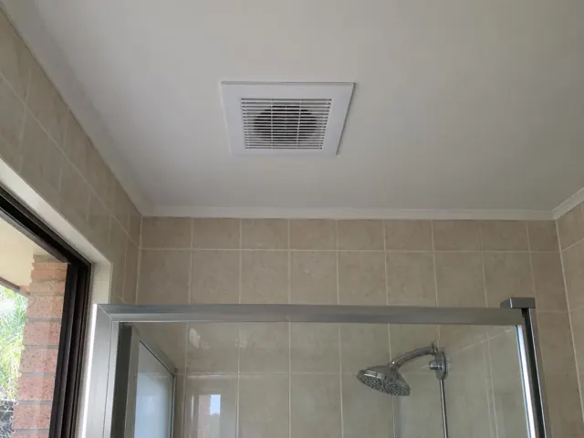Ceiling exhaust fan above a tiled shower in a bathroom with glass screen in Bundall